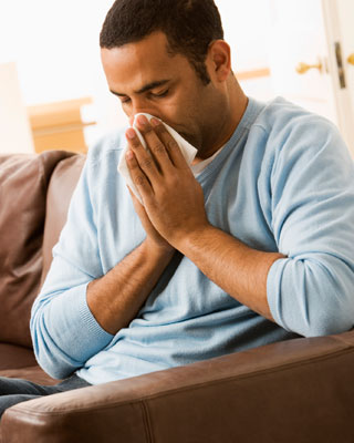 Man blowing his nose into a tissue